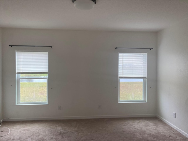 carpeted spare room featuring baseboards