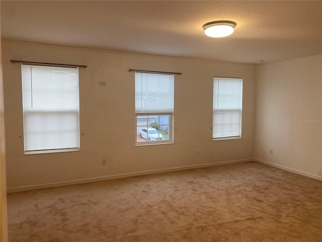 carpeted empty room with a textured ceiling and baseboards