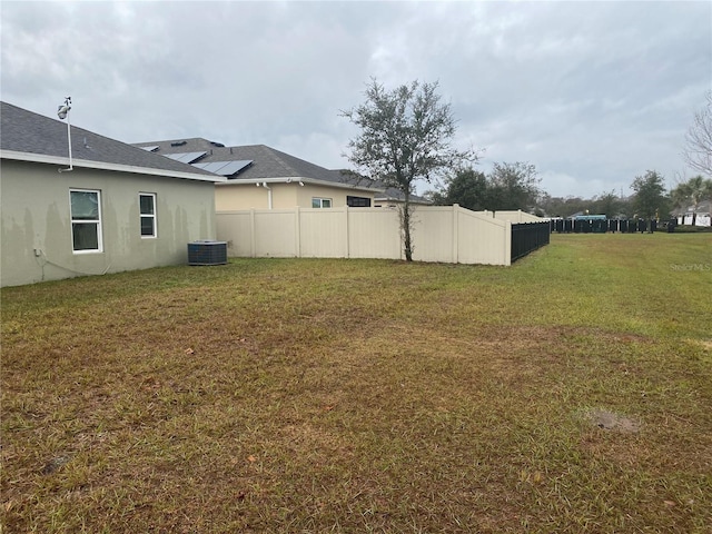 view of yard featuring fence and central AC