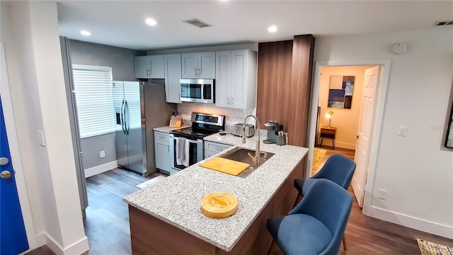 kitchen featuring appliances with stainless steel finishes, light stone countertops, visible vents, and tasteful backsplash