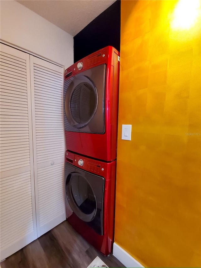 laundry area with wood finished floors, stacked washer and clothes dryer, and laundry area