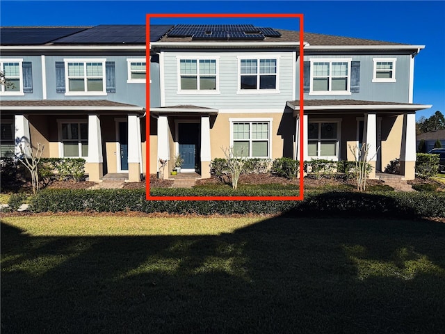 view of property featuring roof mounted solar panels and a front yard