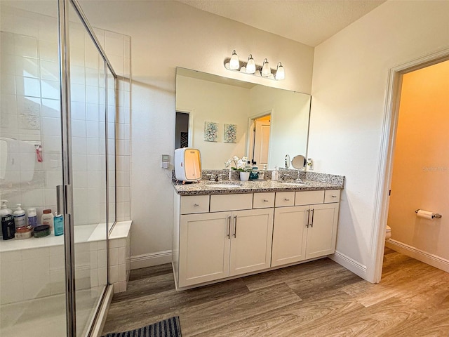 full bathroom featuring baseboards, toilet, wood finished floors, and a shower stall