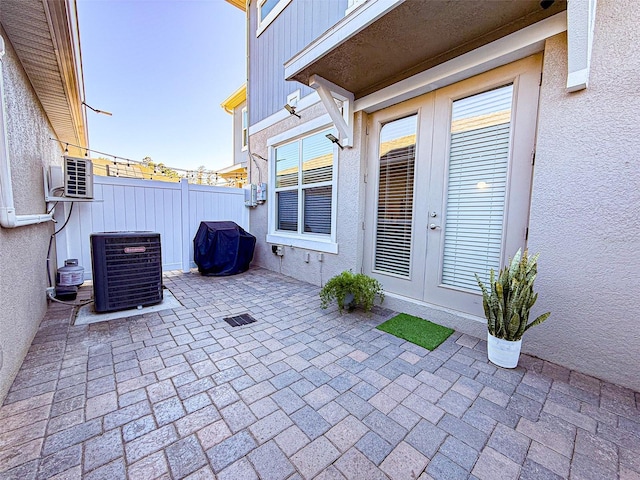 view of patio with french doors, fence, and central AC