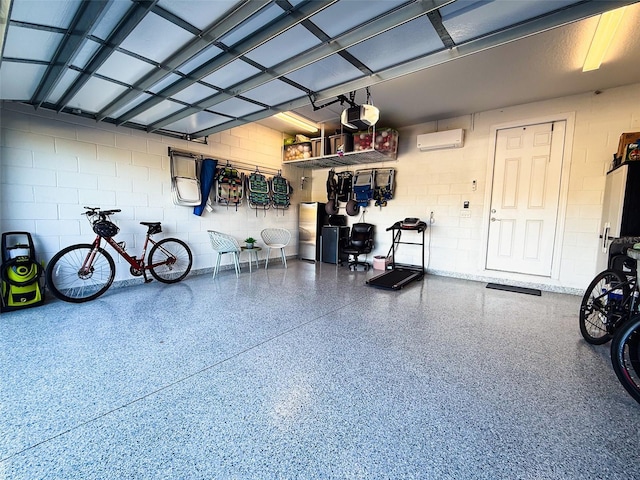 garage featuring an AC wall unit, concrete block wall, and a garage door opener