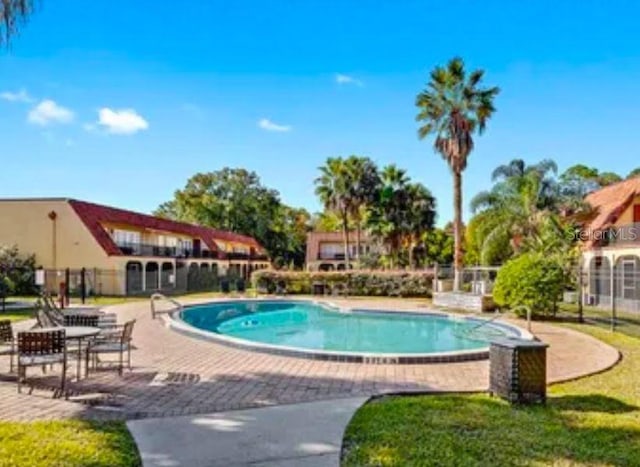 view of swimming pool featuring a patio and fence