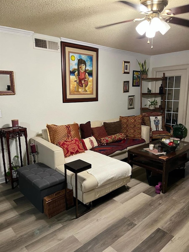 living room featuring crown molding, wood finished floors, visible vents, and a textured ceiling