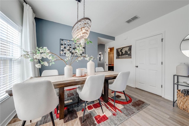 dining area with an inviting chandelier, wood finished floors, visible vents, and baseboards