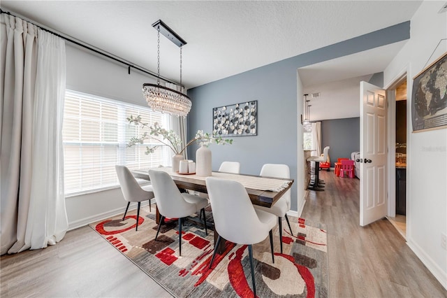 dining space featuring baseboards and light wood finished floors