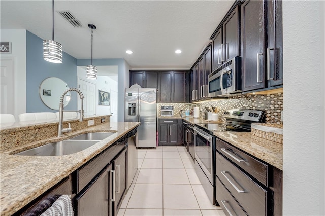 kitchen with visible vents, light stone countertops, decorative backsplash, stainless steel appliances, and a sink