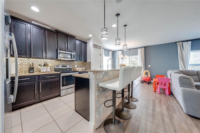 kitchen with decorative backsplash, plenty of natural light, open floor plan, and stainless steel appliances