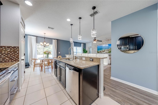 kitchen featuring a sink, stainless steel appliances, backsplash, and visible vents