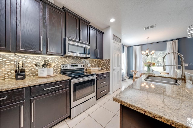 kitchen featuring visible vents, light tile patterned floors, light stone counters, appliances with stainless steel finishes, and a sink