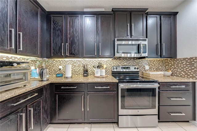 kitchen featuring stainless steel appliances, light stone countertops, decorative backsplash, and a toaster