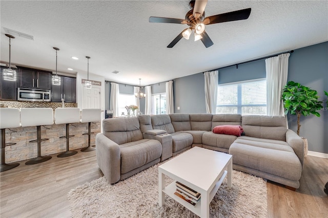 living area featuring light wood-type flooring, a textured ceiling, and a healthy amount of sunlight