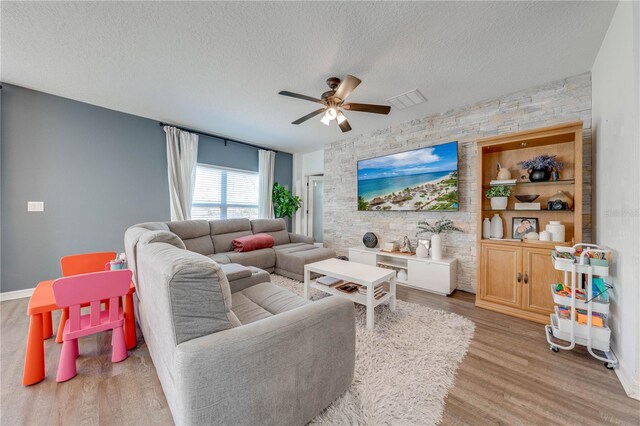 living room featuring visible vents, a textured ceiling, ceiling fan, and wood finished floors