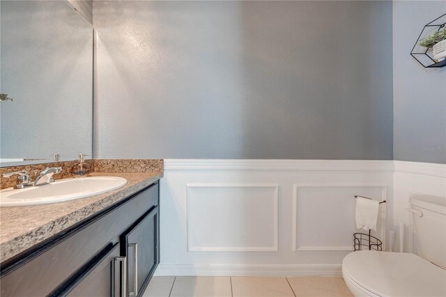 half bathroom with toilet, vanity, and tile patterned flooring