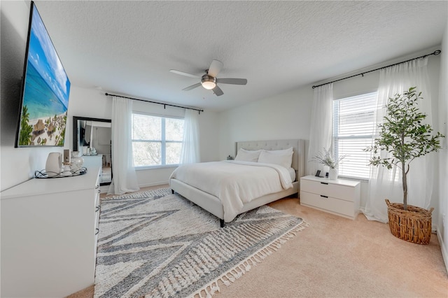 bedroom featuring light carpet, a textured ceiling, and a ceiling fan