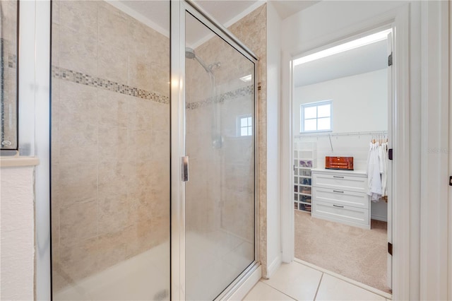 full bathroom with tile patterned floors, a shower stall, tile walls, and a walk in closet