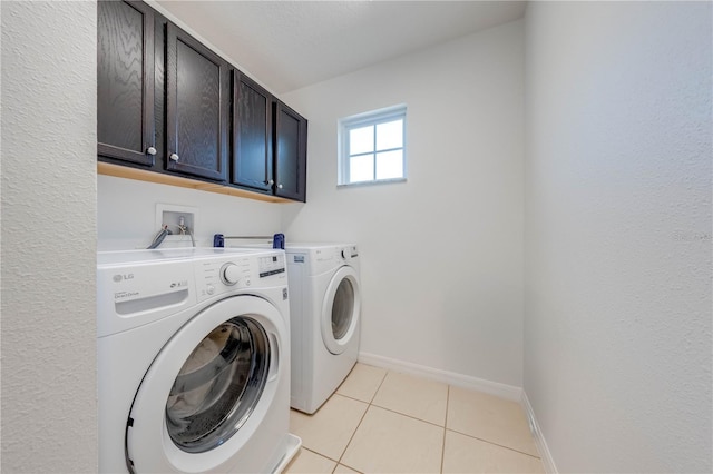 washroom with washing machine and dryer, light tile patterned floors, cabinet space, and baseboards