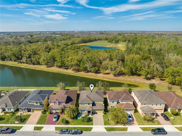 drone / aerial view featuring a wooded view, a residential view, and a water view