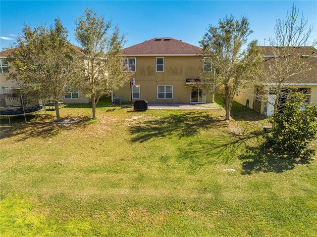 rear view of house with a yard, a patio, and a trampoline