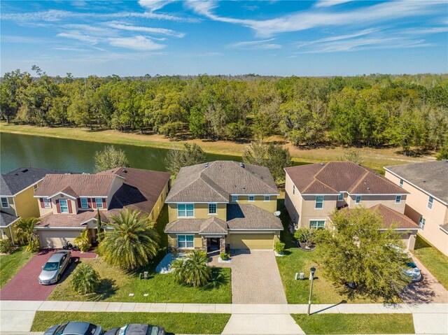 drone / aerial view with a view of trees, a water view, and a residential view