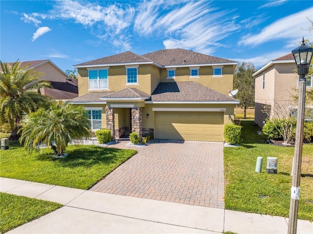 view of front of home featuring a front lawn, stucco siding, decorative driveway, a garage, and stone siding