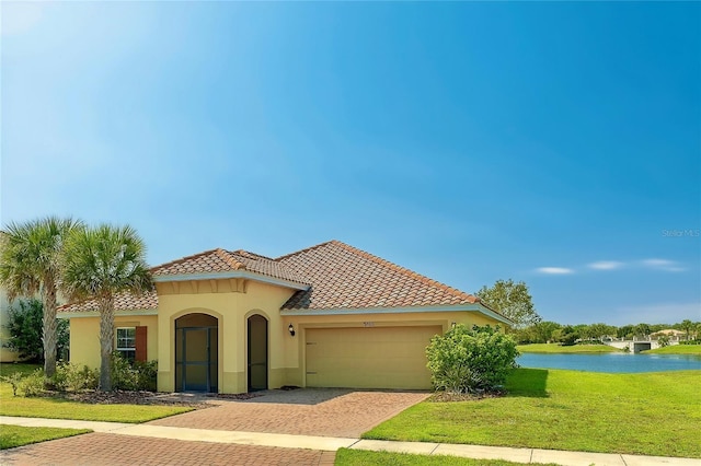 mediterranean / spanish home featuring stucco siding, a water view, a front lawn, decorative driveway, and an attached garage