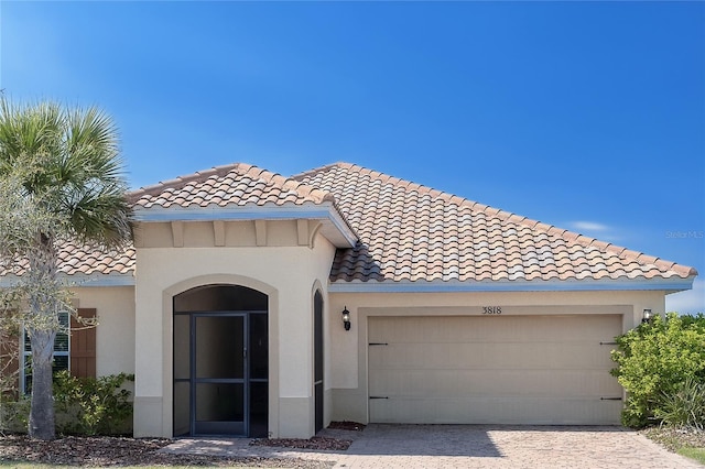 mediterranean / spanish house with a tile roof, a garage, and stucco siding