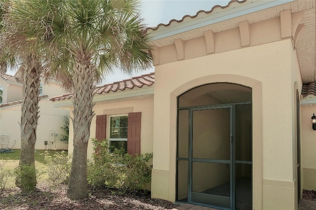 doorway to property with stucco siding and a tiled roof