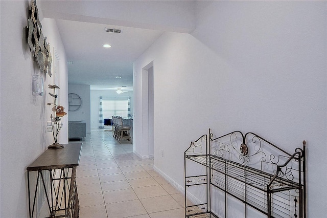 corridor with light tile patterned floors, visible vents, and baseboards