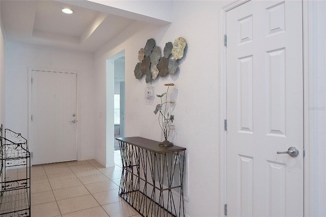 foyer entrance with light tile patterned floors, baseboards, a raised ceiling, and recessed lighting