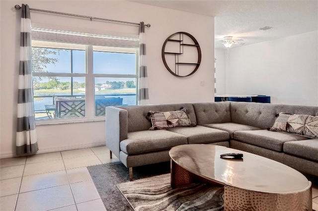 living area featuring light tile patterned floors, a ceiling fan, visible vents, and a textured ceiling