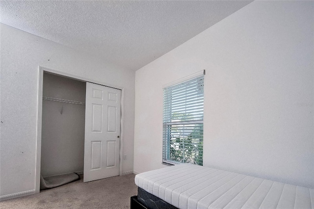 carpeted bedroom with a closet and a textured ceiling