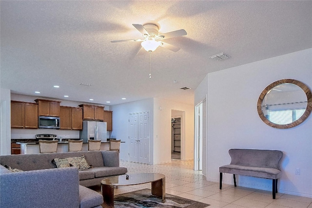 living area featuring visible vents, ceiling fan, light tile patterned floors, recessed lighting, and a textured ceiling