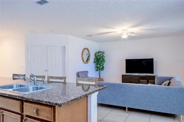 kitchen featuring visible vents, ceiling fan, light tile patterned floors, a textured ceiling, and a sink