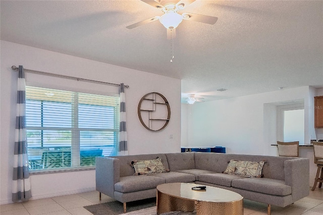 living room featuring a textured ceiling, light tile patterned floors, and ceiling fan