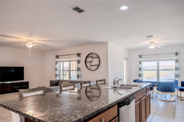 kitchen with a spacious island, light tile patterned flooring, a sink, stainless steel dishwasher, and open floor plan