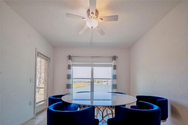 dining space featuring light tile patterned floors, a ceiling fan, baseboards, and a textured ceiling