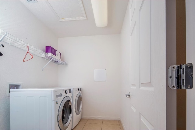 clothes washing area featuring washer and dryer, baseboards, light tile patterned flooring, and laundry area