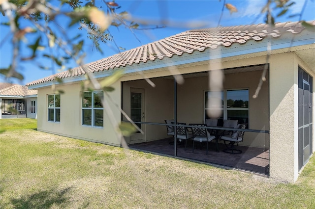 rear view of property featuring a tile roof, a yard, a patio area, and stucco siding