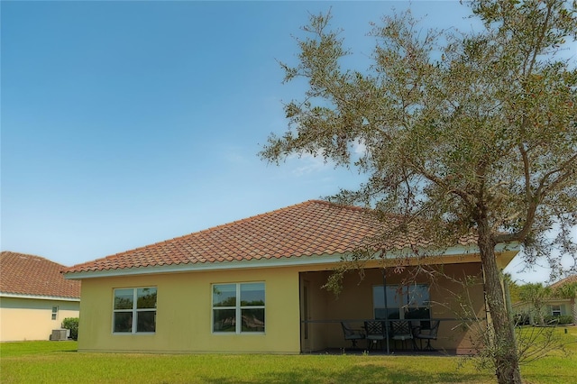 back of house with a patio area, a tile roof, a lawn, and stucco siding