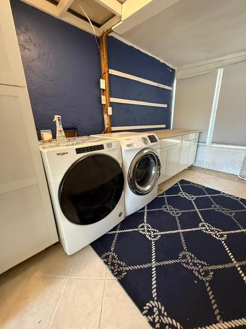 washroom with tile patterned flooring, washing machine and dryer, and cabinet space