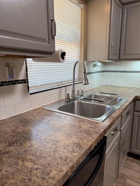 kitchen with a sink, decorative backsplash, dishwashing machine, and gray cabinets