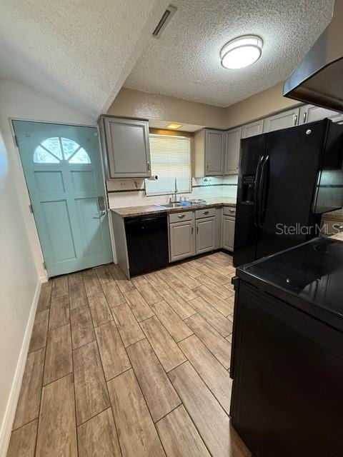 kitchen with wood tiled floor, a sink, gray cabinetry, black appliances, and light countertops