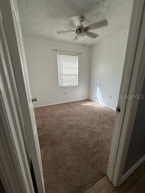 unfurnished room featuring baseboards, carpet, ceiling fan, and a textured ceiling