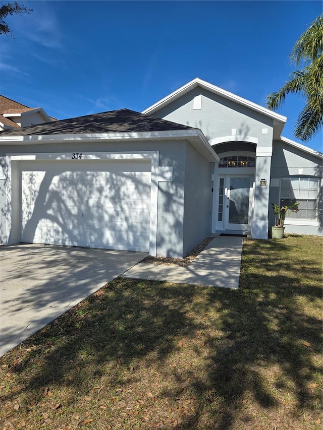 ranch-style house featuring stucco siding, a front lawn, concrete driveway, and an attached garage