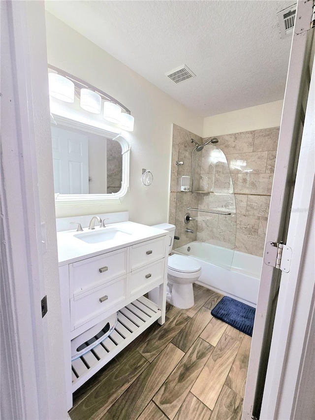 full bath with visible vents, toilet, a textured ceiling, shower / tub combination, and vanity