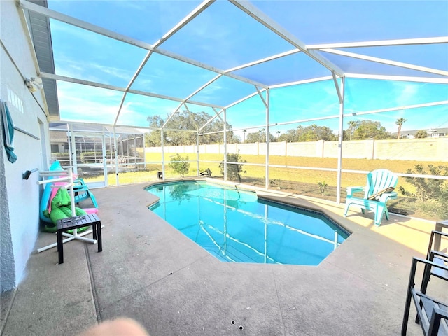 view of pool with glass enclosure, a fenced backyard, and a patio area